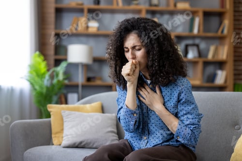 Preview: Sick woman coughing at home on sofa, suffering from cold or flu virus