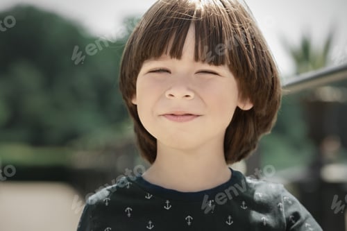 Preview: Child screwed up his eyes on a sunny day, face portrait