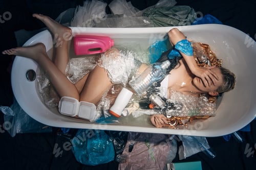 Preview: top view of young woman lying in bathtub with facepalm among trash, environmental pollution concept