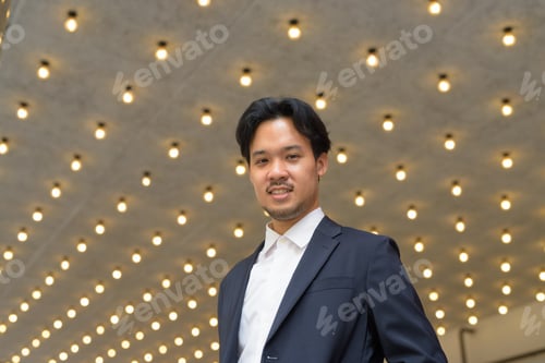 Preview: Portrait of Asian businessman smiling outdoors in the city