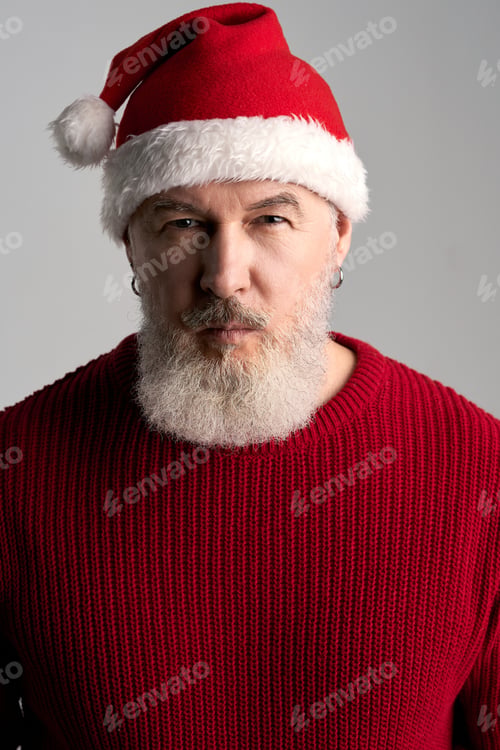 Preview: Portrait of trendy middle aged man with beard wearing Christmas hat and red sweater looking at