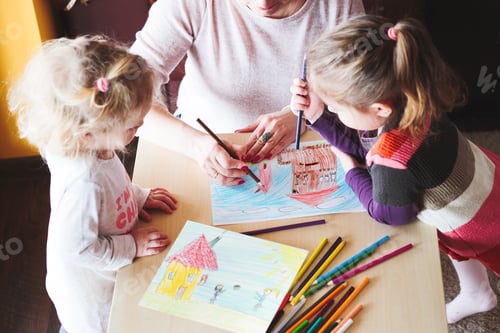 Preview: Mom with little girls drawing a colorful pictures of house and playing children using pencil crayons