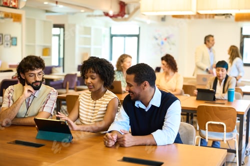 Preview: Diverse professionals collaborating using tablet in modern coworking space