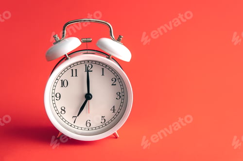 Preview: White alarm clock on a blurred red background.