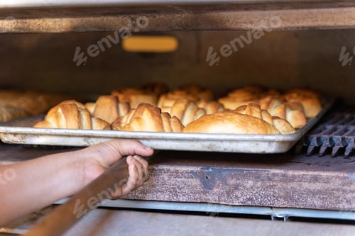 Preview: Person taking pastries out of an industrial oven