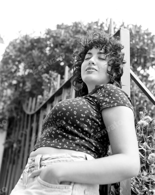 Preview: Young woman leaning against railing enjoying warm summer day in monochrome