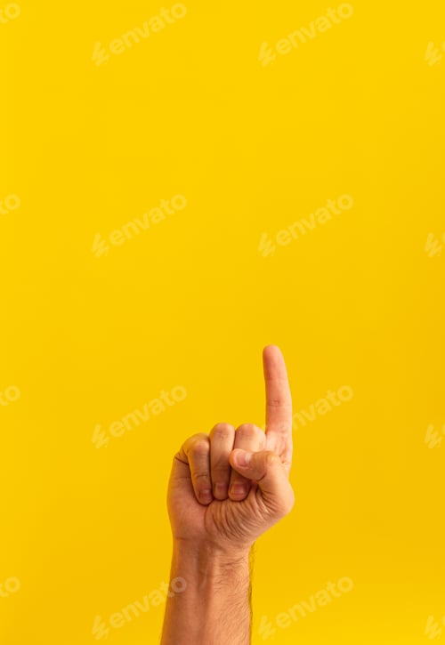 Preview: Closeup of a person pointing up isolated on a yellow background with space for text