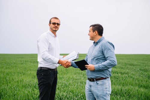 Two farmer standing in a green wheat field and shake hands. Two farmer standing in a green wheat field and shake hands.