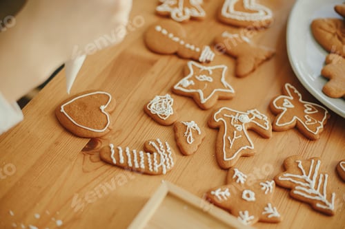 Preview: Decorating christmas gingerbread cookies with icing on wooden table close up. Holiday preparations