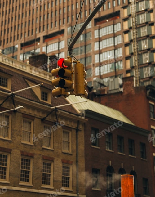 Preview: city traffic light showing red with a backdrop of urban buildings and architectural details.