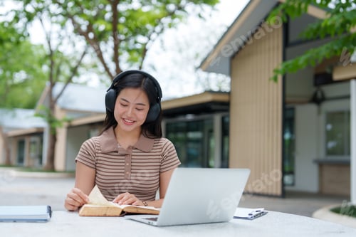 Preview: Young Woman Studying Outdoors with Headphones and Laptop