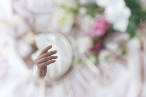 Preview: Hand reflected in mirror on background of soft fabric with flowers and gift. Womens and Mothers day