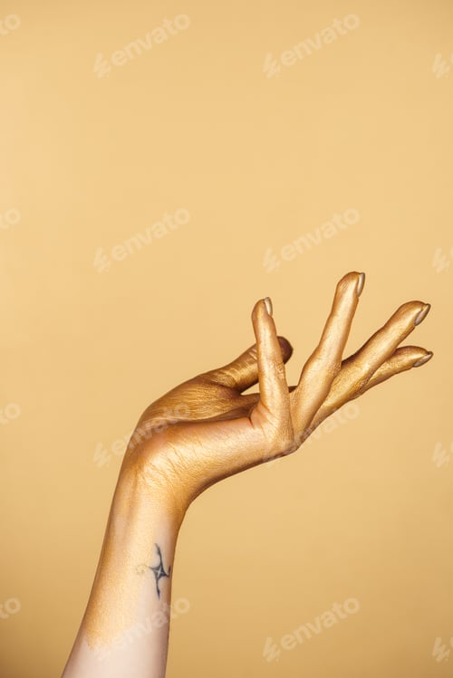 Preview: cropped view of female painted hand with tattoo isolated on gold