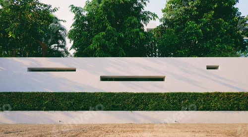 Preview: Front view of white concrete wall decoration with bush fence and green trees in front of home