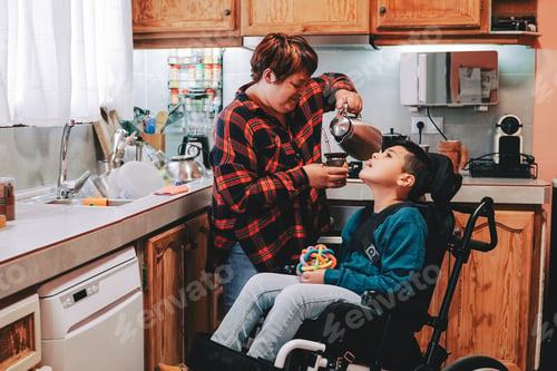 Preview: Latin mother taking care of son with disability on wheelchair inside home kitchen - Focus on child