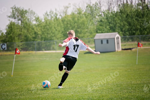 Preview: A blond, teenage boy playing soccer on an outdoor pitch.