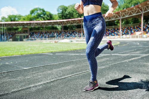 Preview: Portrait of a strong fit girl in sportswear running in the stadium.