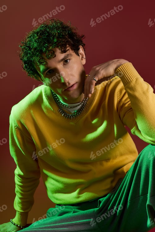 Preview: Stylish man in vibrant yellow sweater poses against an artistic backdrop