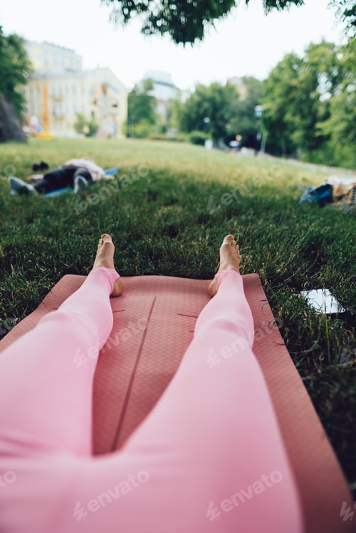 Preview: The girl's legs are on a yoga mat in the park.