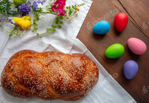 Preview: Easter sweet bread, homemade tsoureki braid and Easter eggs on a white cloth on the table,