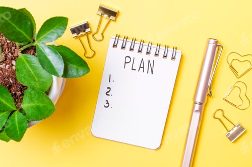 Preview: Notepad with the inscription plan on yellow background close-up top view.