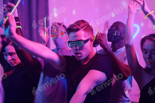 Preview: Excited guy and his intercultural friends with glowing sticks dancing together