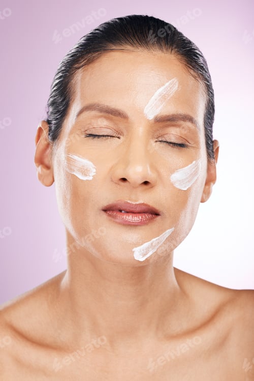 Preview: Face, cream and skincare of woman with eyes closed in studio isolated on a purple background. Matur