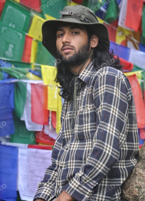 Preview: A good looking male tourist looking at camera while posing against Buddhist prayer flags