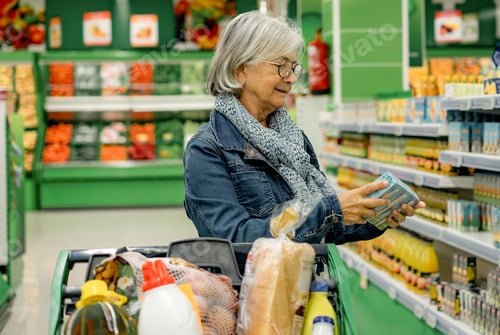 Preview: Smiling senior woman with glasses pushing a shopping cart at the supermarket