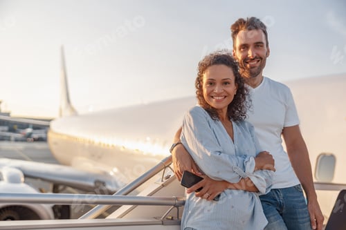 Preview: Portrait of happy couple of tourists, man and woman looking excited while standing together outdoors