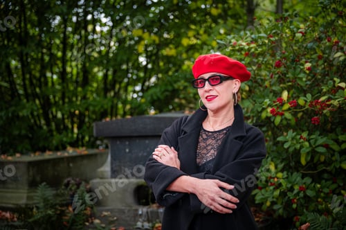 Preview: Stylish mature woman in red beret outdoors in autumn park