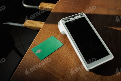 Preview: Contactless card and payment terminal on table in sunlit cafe, ready for transaction.
