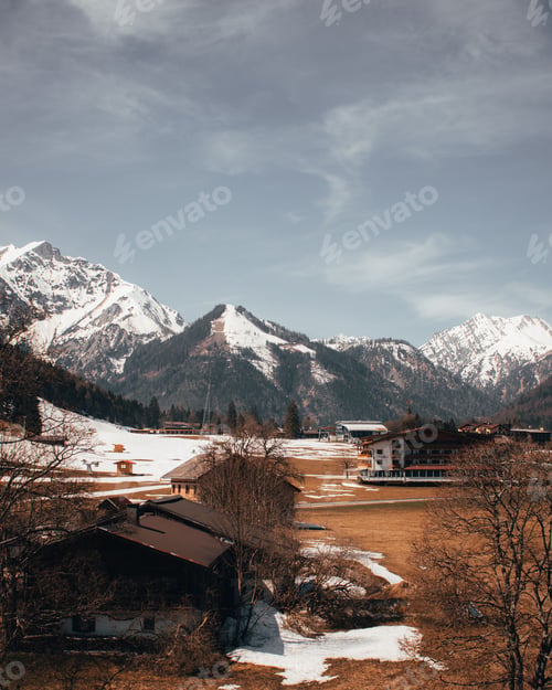Preview: Picturesque winter scene with a snow-covered field, small buildings, and a forest in the foreground