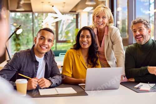 Preview: Multi-Cultural Business Team Meeting Around Laptop In Modern Office