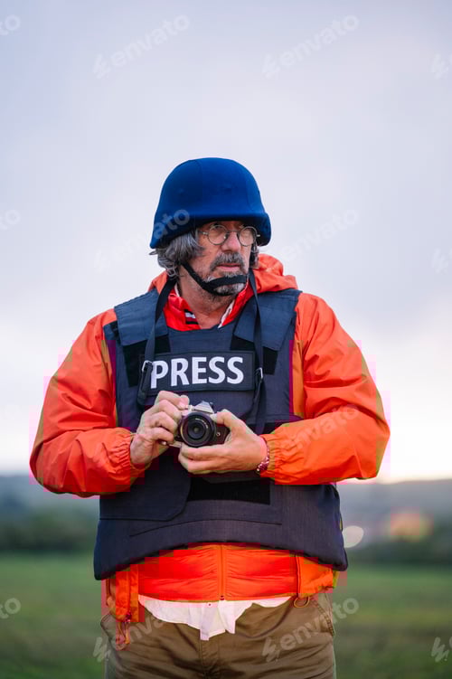 Preview: Reporter in bulletproof vest holding a camera.