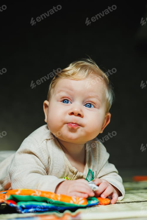 Preview: A small child in a white bodysuit is learning to crawl on a clean, heated floor. Home photo of a