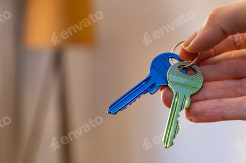 Preview: hand holding keys with room on background. rent sell buy apartment real estate business