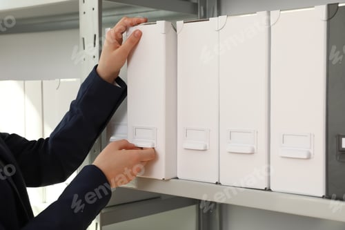 Preview: Woman taking folder with documents from shelf in archive, closeup