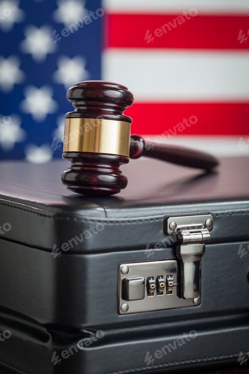 Preview: Leather Briefcase and Gavel Resting on Table with American Flag Behind.