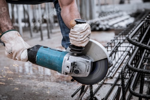 Preview: A worker cuts some iron rods with an electric saw causing sparks.