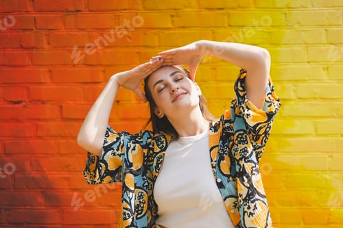 Preview: Portrait of happy smiling young woman with sunglass on colorful orange background