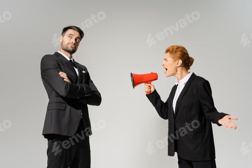 Preview: irritated businesswoman shouting at calm and confident manager standing with folded arms isolated on