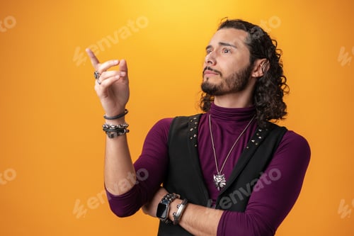 Preview: Handsome brunette man with beard and curly hair pointing at copy space