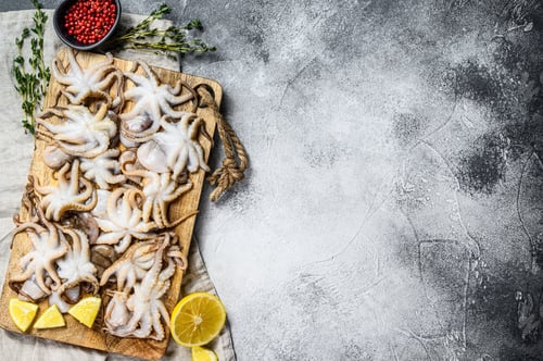 Preview: Raw octopus with thyme and lemon in a wooden bowl. Organic seafood