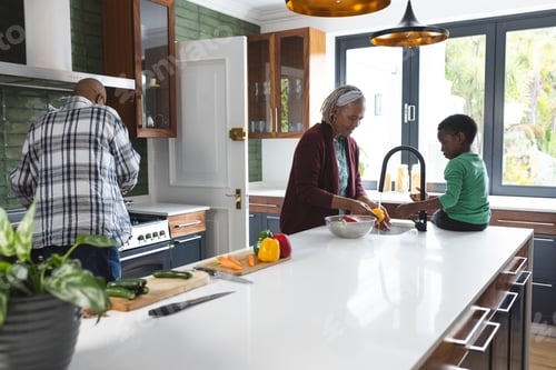 Preview: Happy african american grandmother and grandson washing vegetables in kitchen, slow motion