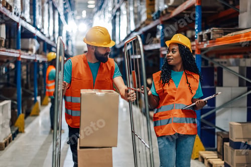 Preview: Warehouse workers discussing logistics while organizing inventory using digital tablet