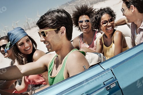 Preview: A group of friends in a pale blue convertible on the open road, driving across a flat plain.