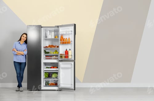Preview: Happy young woman near open refrigerator indoors, space for text