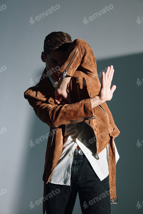 Preview: Attractive man in brown coat gesturing with his hands on gray background cropped view