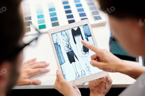 Preview: One of young fashion designers pointing at tablet display during discussion